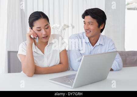 Couple using laptop with woman talking on phone Stock Photo