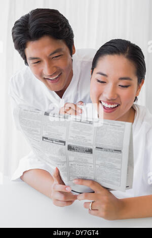 Couple in bathrobes reading newspaper together in the morning Stock Photo