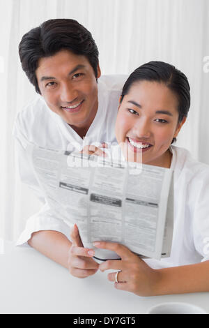 Couple in bathrobes reading newspaper together in the morning Stock Photo