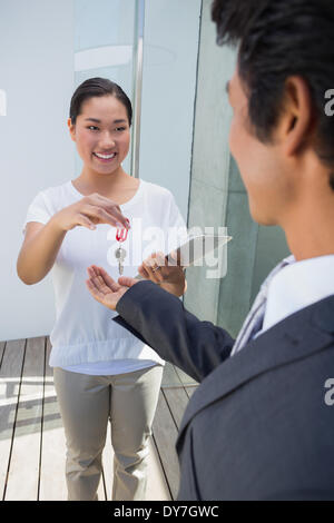 Estate agent giving house key to buyer Stock Photo