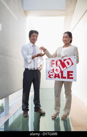 Estate agent giving keys to new home owner Stock Photo