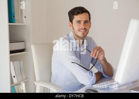 Casual businessman smiling at camera at his desk Stock Photo