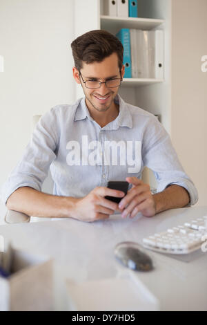 Happy young businessman reading a message on mobile phone while sitting ...