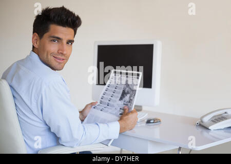 Casual businessman reading newspaper at his desk Stock Photo