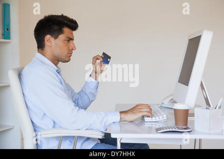 Casual businessman shopping online at his desk Stock Photo