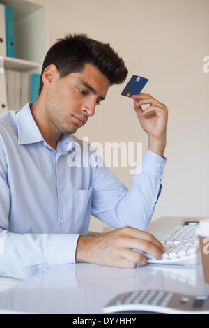 Casual businessman shopping online at his desk Stock Photo