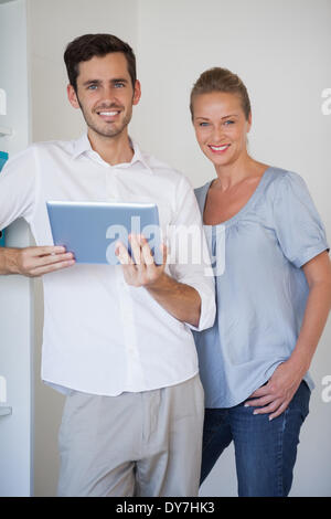 Casual business team smiling at camera man holding tablet Stock Photo