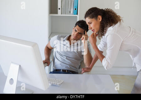 Casual business team looking at computer together at desk Stock Photo