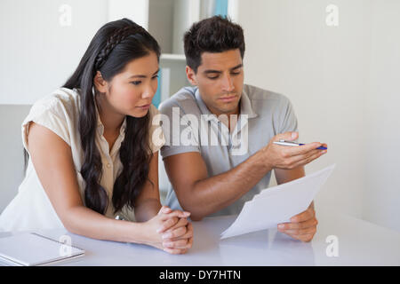 Casual business team reading document together at desk Stock Photo