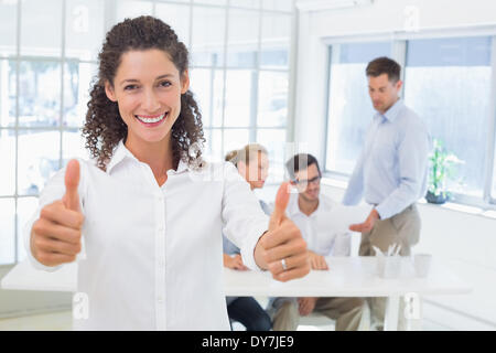 Casual happy businesswoman showing thumbs up to camera Stock Photo