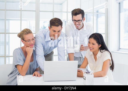 Casual business team looking at laptop together Stock Photo