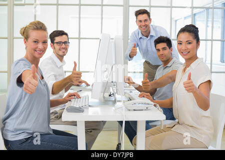 Casual business team smiling at camera showing thumbs up Stock Photo