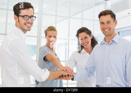 Casual smiling business team putting their hands together Stock Photo