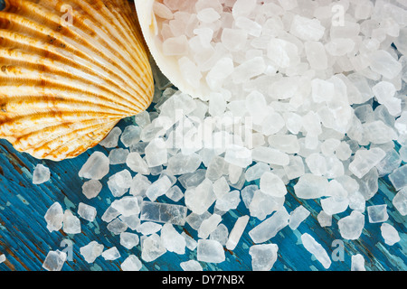 Sea salt crystals in shell on old painted board as background Stock Photo