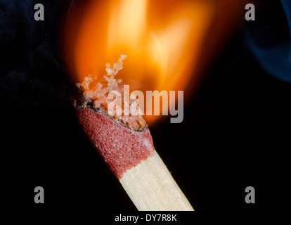 Match being lit showing flame at the point of ignition, on a black background. Burning match after being ignited. Stock Photo