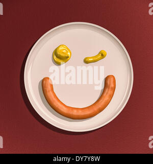 Sausage and drops of mustard, winking smiley face on a plate Stock Photo