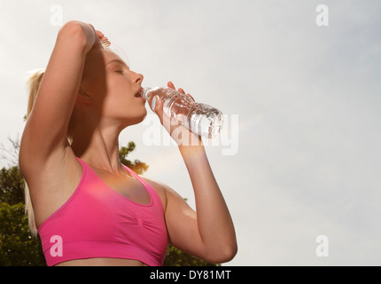 Young woman drinking water from bottle after running with lens flare Stock Photo