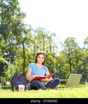 Girl writing in a notebook and looking at camera outdoors Stock Photo