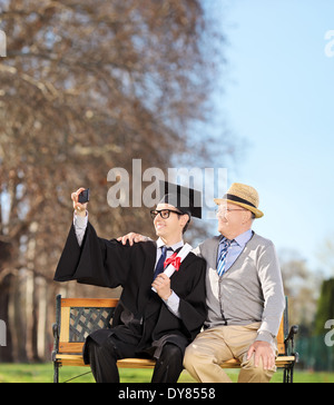 Male student and his proud father taking selfie in park Stock Photo