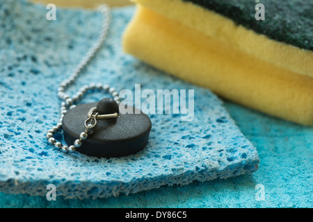 Daily washing up chores cleaning cutlery with sponge scourer and plug on chain for washing the dishes Stock Photo