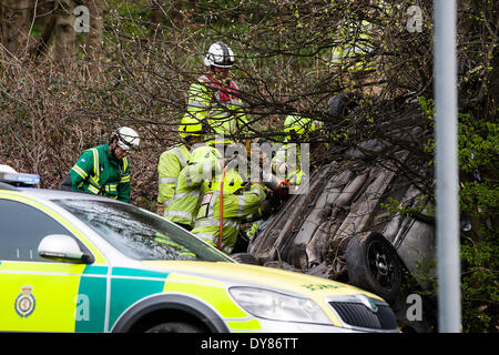 Queenswood Drive, Leeds West Yorkshire UK 9th April 2014. Emergency services attend an incident at around 1400 hours in which a vehicle overturned in a busy suburban street. Two persons were cut free from the vehicle which ended up on its roof in woodland at the side of the road in the Becketts Park LS6 area and removed from the scene by ambulance. The West Yorkshire Air Ambulance also attended the scene but was not used to transport casualties. Another vehicle, a yellow Seat Ibiza, which was seen to be damaged was also parked nearby. Credit:  Ian Wray/Alamy Live News Stock Photo