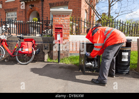 Postman collecting mail from a box outside the Old Post Office, Plumtree, Nottinghamshire, England, UK Stock Photo