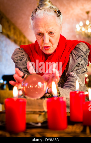 Female Fortuneteller or esoteric Oracle, sees in the future by looking into their crystal ball during a Seance Stock Photo