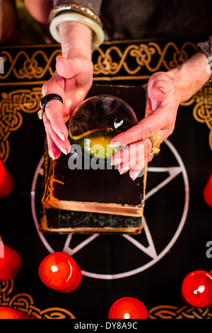 Female Fortuneteller or esoteric Oracle, sees in the future by looking into their crystal ball during a Seance Stock Photo