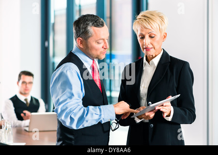 Business - meeting in office, two senior managers are discussing a document on tablet computer Stock Photo