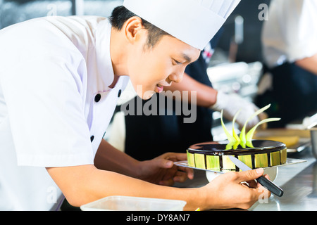 Side view of young chef decorating cake Stock Photo