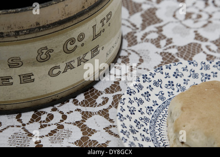 Vintage Cake Tin and Saucer with a scone on a flora tablecloth Stock Photo