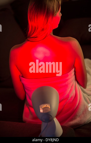 Young woman in pain, warms up with a red light Stock Photo