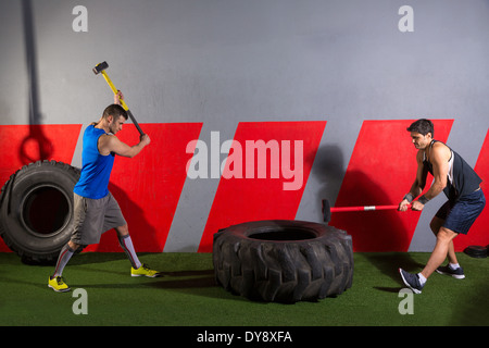 Sledgehammer Tire Hits men workout at gym with hammer and tractor tire Stock Photo