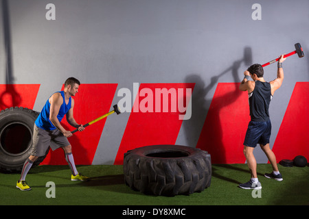 Sledgehammer Tire Hits men workout at gym with hammer and tractor tire Stock Photo