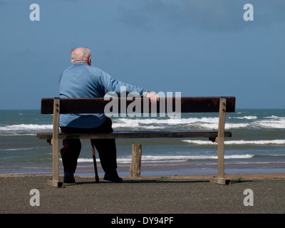 old man sat on a public bench overlooking the sea, Bude, Cornwall, UK Stock Photo