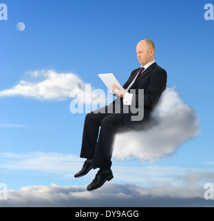 a businessman sitting on a cloud with a tablet pc Stock Photo
