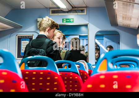 Teenage school children in uniform queuing to get off a train Stock Photo