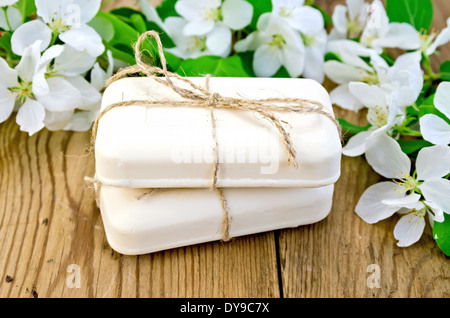 Two bars of soap with white flowers of apple trees on the background of wooden boards Stock Photo