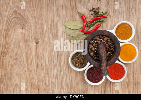 Mortar and pestle with pepper and spices on wooden table Stock Photo