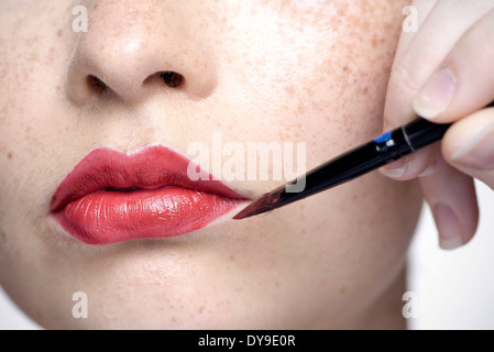 Young woman applying lipstick with lip brush, close-up Stock Photo