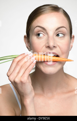 Young woman biting into carrot Stock Photo