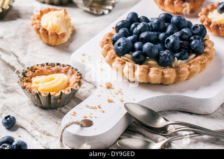 Blueberry tarts served on white cutting board with vintage teaspoons. Stock Photo