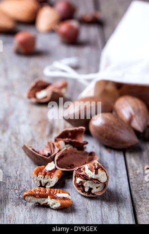 Whole and chopped pecan nuts on old wooden table. Stock Photo