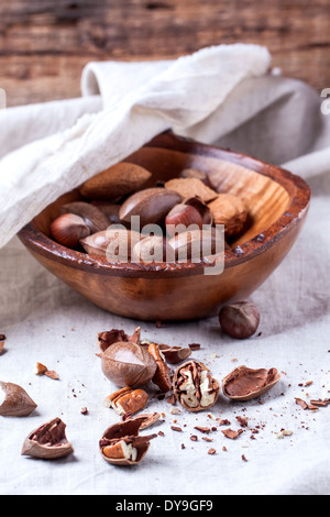 Wooden bowl with whole and chopped pecan nuts over gray textile Stock Photo