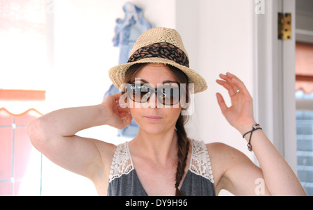 Young woman 20s wearing Ray Ban sunglasses and straw truly style hat summer fashion Photograph taken by Simon Dack Stock Photo