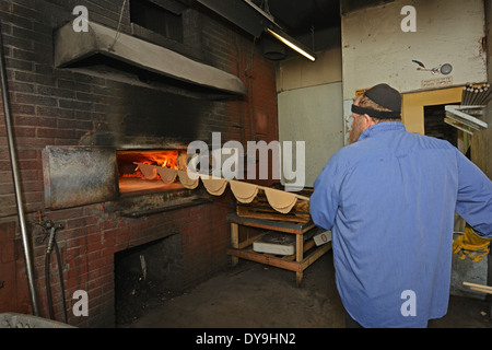 A religious Jewish man putting matzoh into the oven at the Borough Park Matzah Bakery in Brooklyn, New York Stock Photo