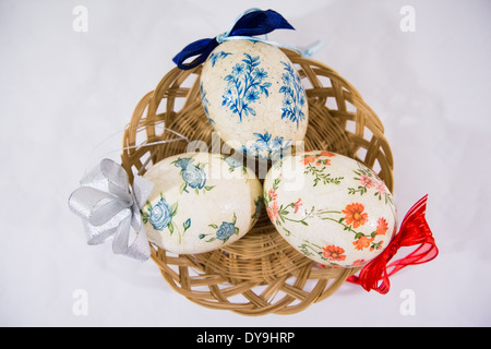 Group of colorful easter eggs decorated with flowers made by decoupage technique, in a basket on light background Stock Photo