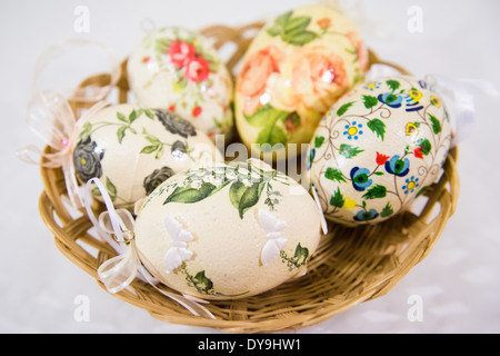 Group of colorful easter eggs decorated with flowers made by decoupage technique, in a basket on light background Stock Photo