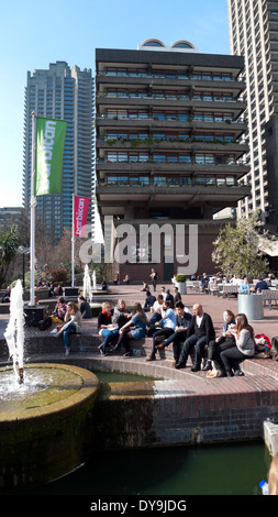 People sitting by the fountain in the sunshine outside the Barbican Centre London England UK KATHY DEWITT Stock Photo