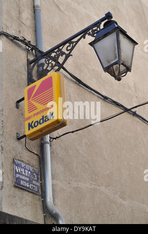 streetlight, kodak illuminated advertising sign and french blue enamel street sign on wall in arles france Stock Photo